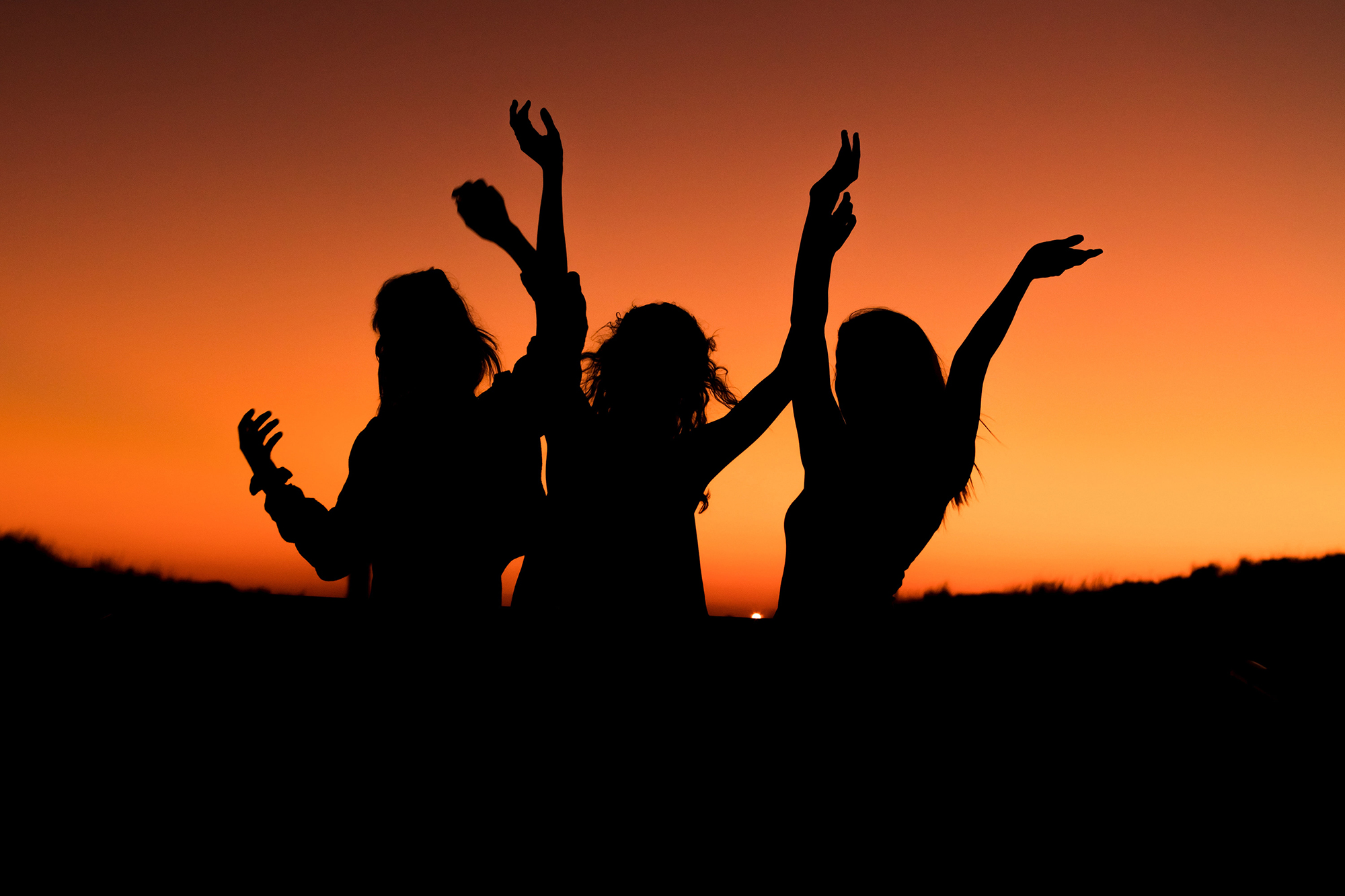 women dancing joyously at sunset