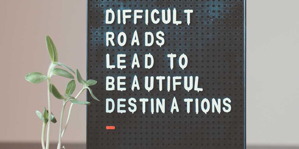 Bulletin board with message Difficult Roads Lead to Beautiful Destinations